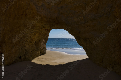 View of the Ocean from a cave in the scenic beach Praia dos Tres Irmaos in Alvor, Algarve, Portugal; Concept for travel in Portugal and Algarve