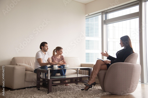 Family relationships expert trying to reconcile young arguing couple. Troubled husband blaming wife in problems in marriage while offended sad spouse sitting next to him during therapy session