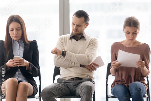 Fototapeta Naklejka Na Ścianę i Meble -  Business people sitting in row, tedious waiting for long time, meeting start delay, someone is late, getting bored, annoyed dissatisfied man looking at wristwatch, wait in queue for interview concept