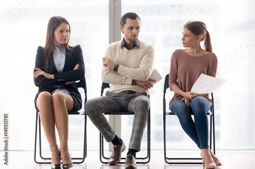 Male and female ambitious job seekers waiting for interview, looking at each other with hate and dislike, feeling jealous envious, rivalry and internal competition, get position and sidestep rivals