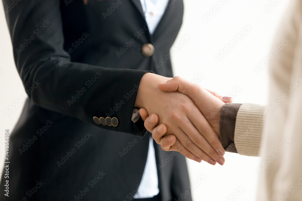 Close up view of businessman and businesswoman shaking hands after closing a deal, confident handshake of female leader executive welcoming business partner on negotiations, teamwork concept