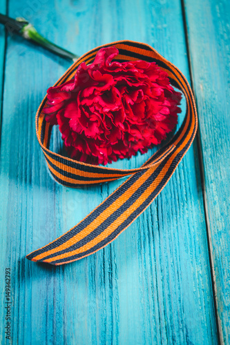 Red carnations and St. George ribbon on wooden background/St. George ribbon - the symbol of the great Victory/Victory Day photo