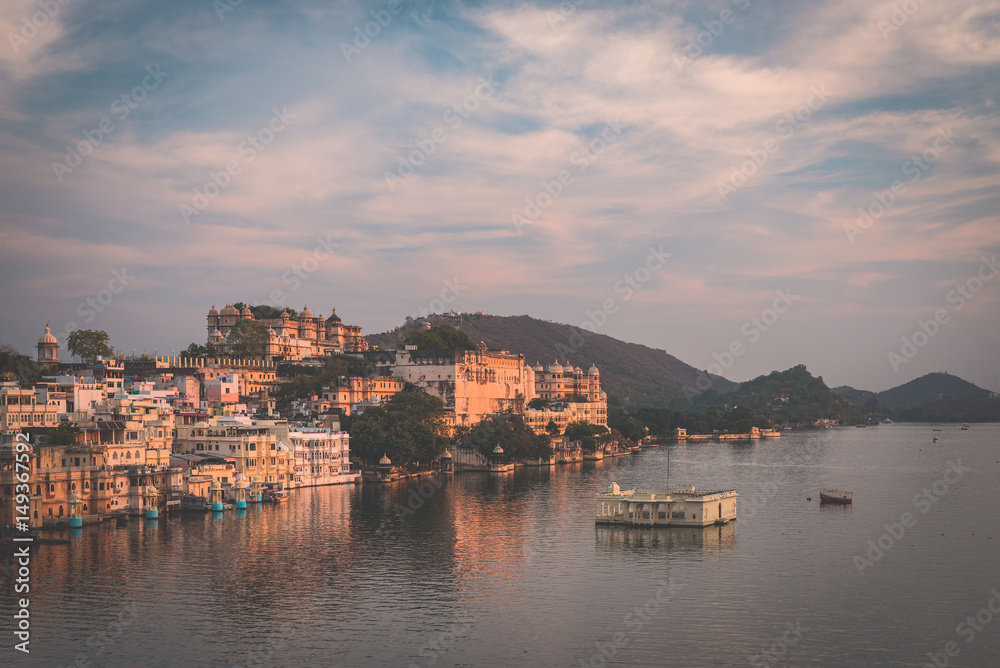 Udaipur cityscape with colorful sky at sunset. The majestic city palace on Lake Pichola, travel destination in Rajasthan, India. Toned image.