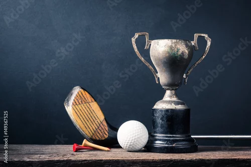 Obraz fotografia martwa: kij golfowy, piłka golfowa i koszulka ze starym trofeum mistrza na starym drewnie na ciemnym tle sztuki
