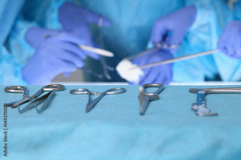 Close up of surgical tools while group of surgeons at work in operating theater. Close up of surgical tools while group of surgeons at work in operating theater.