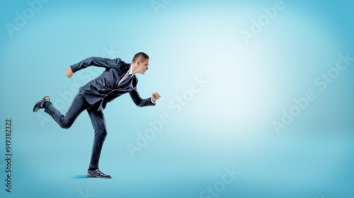 A businessman in a runner position ready to start on blue background. New business.