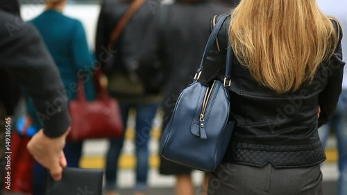 Woman on city street is unaware that her purse has been stolen by crafty pickpocket. She crosses the road through a pedestrian crossing. The thief stole her wallet from the bag