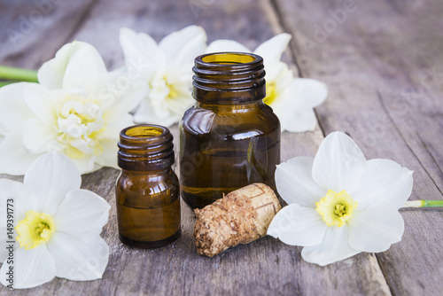 Fototapeta Naklejka Na Ścianę i Meble -  vials with essential oil and narcissus flowers on rustic wooden background, selective focus