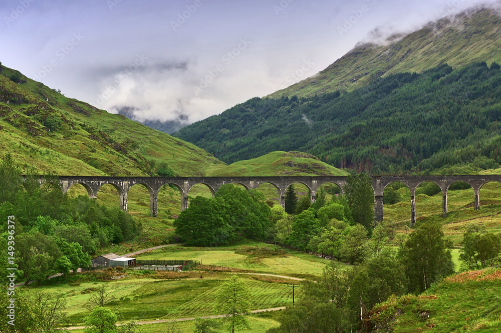 Viaduct leading across a green valley with a mountain ridge in the background