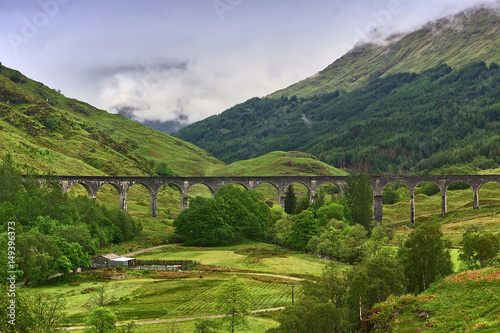 Cuadro en lienzo Viaduct leading across a green valley with a mountain ridge in the background