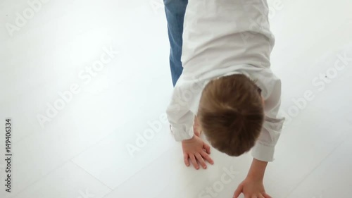 the father raises the son by the leg and he goes to the floor and fooling around at home