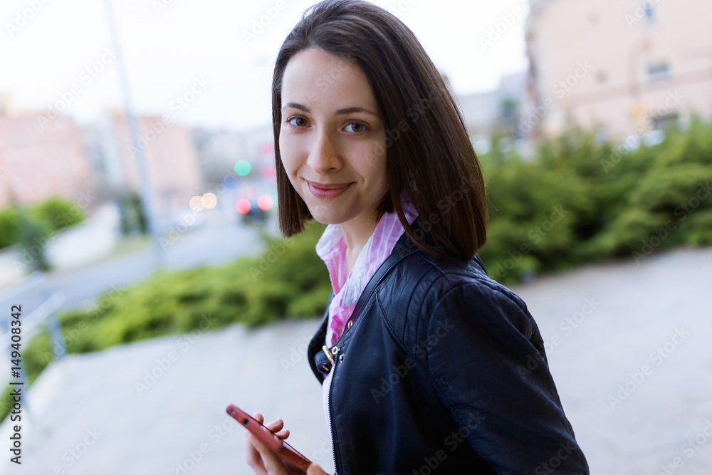 Beautiful young woman using her mobile phone in the street. Beautiful young woman using her mobile phone in the street.