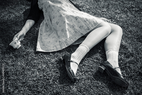 Young woman portrait, faceless, on the prairie - She is lying down on the grass with a China bone teacup in one hand