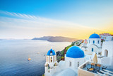 Classical view from sunset point at Oia village white and blue architecture, Santorini island, Greece. Incredible evening scenery.