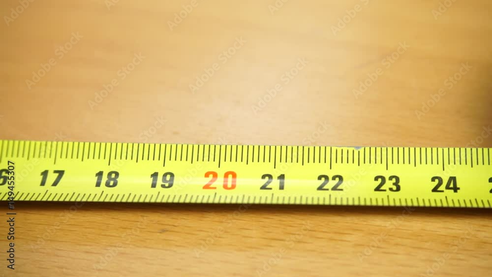 Tape measure on the brown wooden background. Construction, engineering, repair concept. Dolly sliding shot 4K ProRes HQ codec