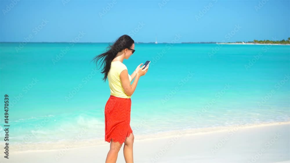 Young woman use phone during tropical beach vacation. Tourist using mobile smartphone. Young woman use phone during tropical beach vacation. Tourist using mobile smartphone.