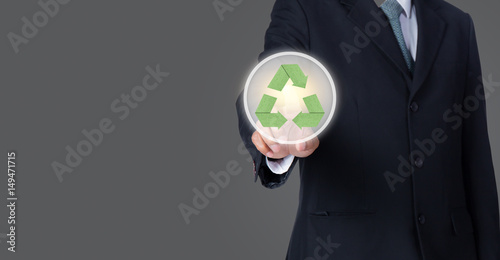 business man pointing at green recycle symbol with gray background