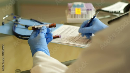 over shoulder doctor writing on a form for a blood test