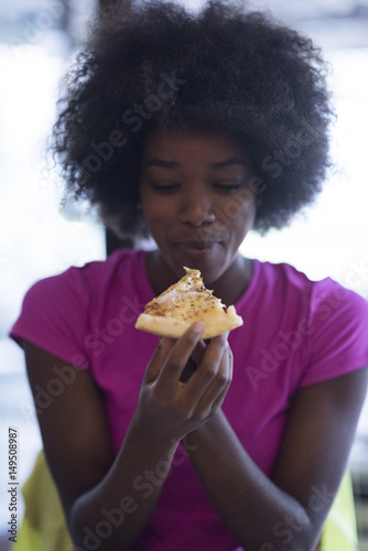 woman with afro hairstyle eating tasty pizza slice