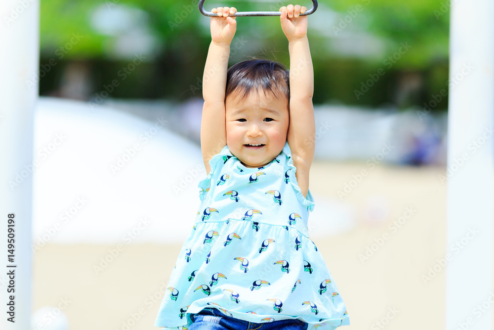 Fototapeta premium 公園の遊具にぶら下がっているかわいい子供