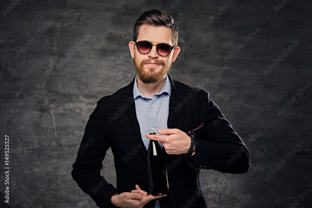 A man dressed in a cotton velvet jacket and sunglasses presenting craft bottled beer. A man dressed in a cotton velvet jacket and sunglasses presenting craft bottled beer.