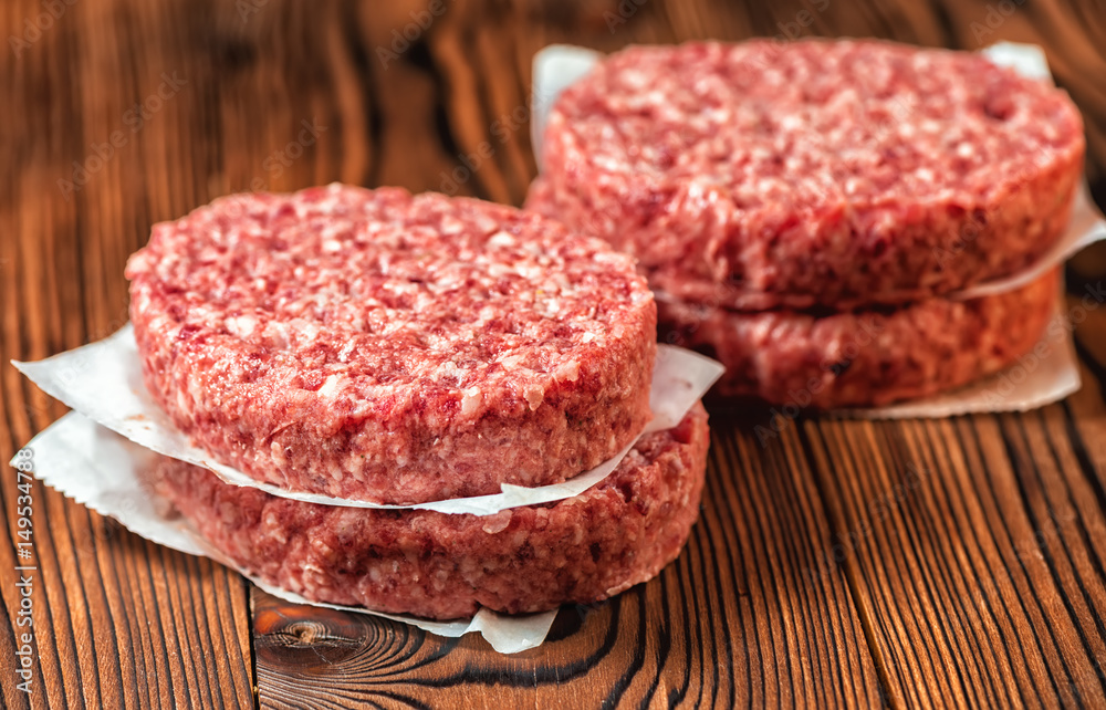 raw ground beef meat hamburger patties on paper, wooden background raw ground beef meat hamburger patties on paper, wooden background