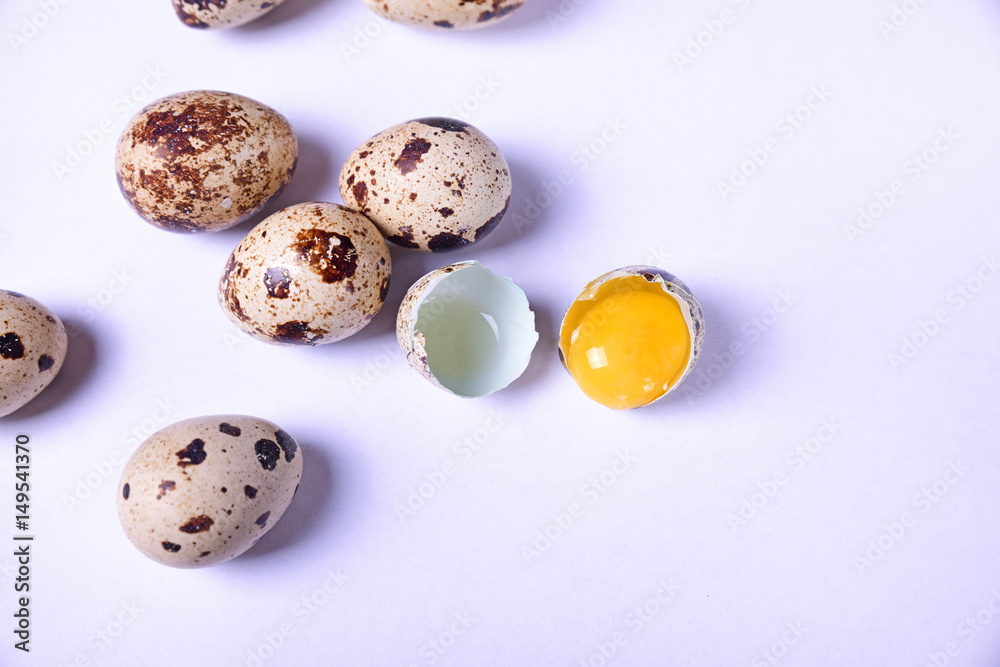 Group of quail eggs and one broken egg with yolk