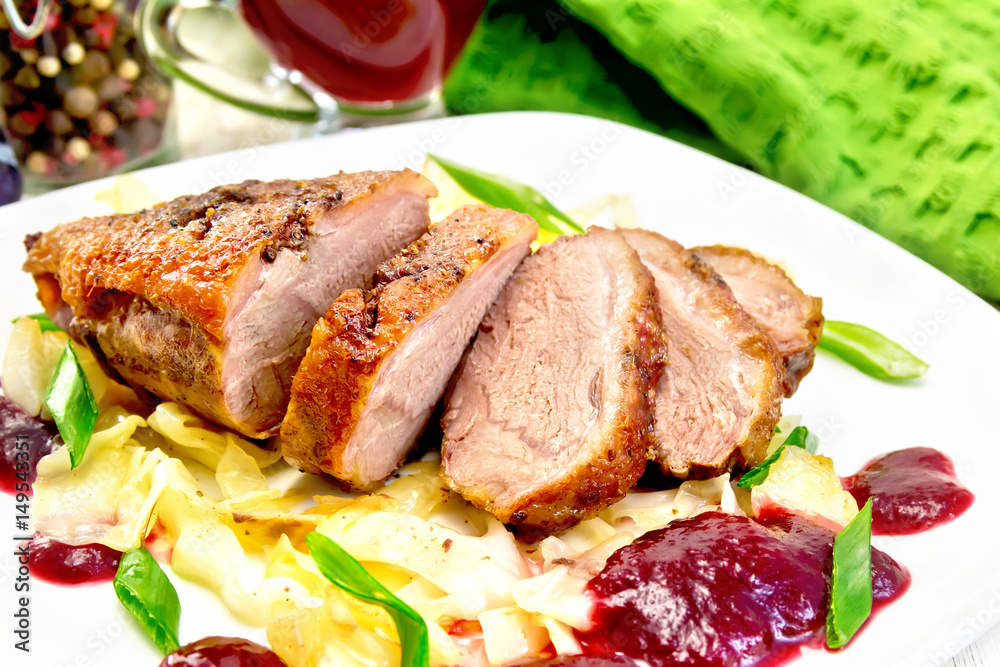 Duck breast with plum sauce and cabbage in plate on light board