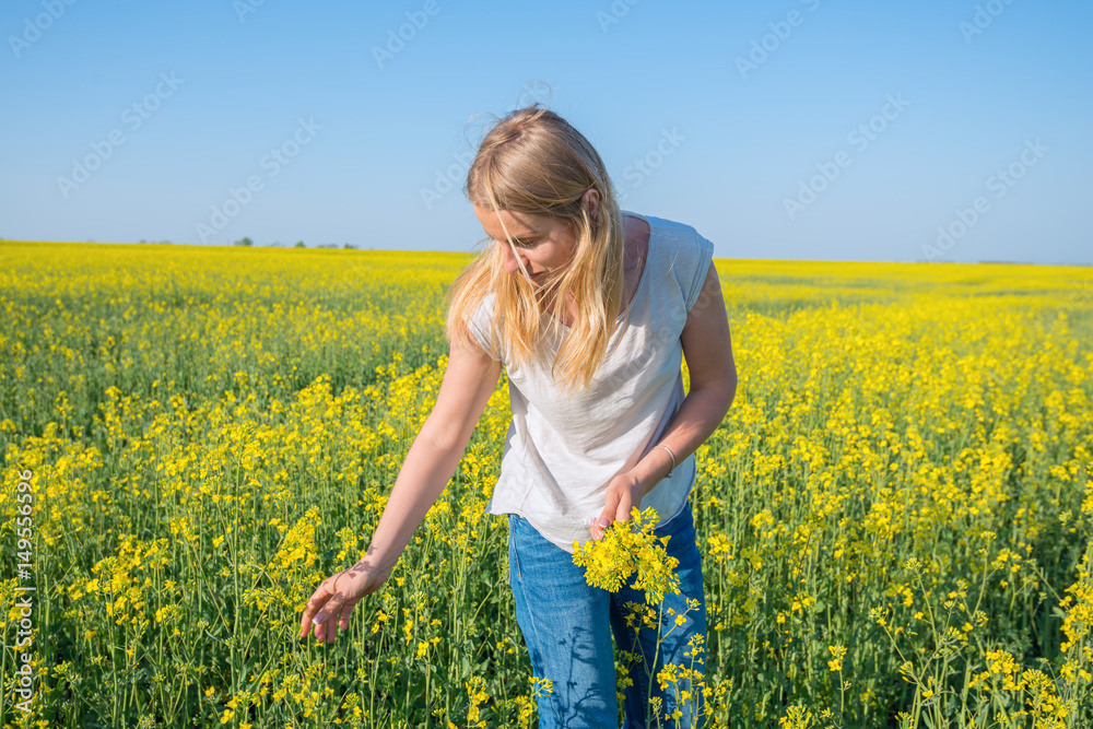 Cute girl, blonde collects yellow flowers in a field under a blue sky Cute girl, blonde collects yellow flowers in a field under a blue sky