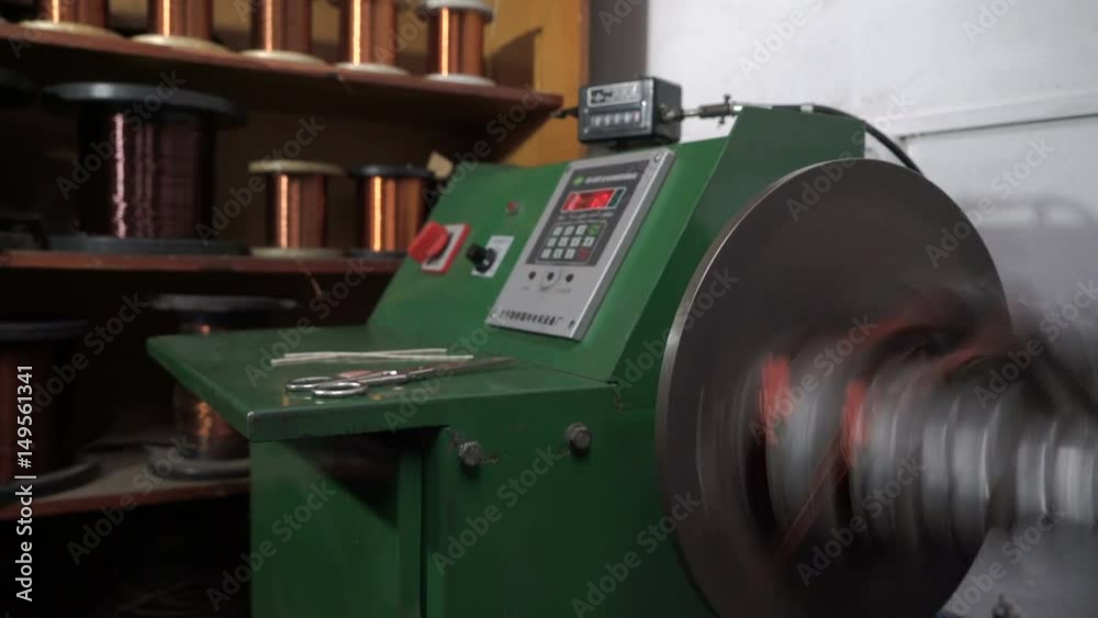 The worker winds the winding of the electric motor. The machine for winding. Electric motor repair
