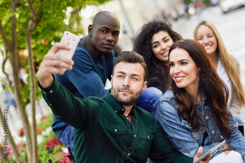 Multi-ethnic young people taking selfie together in urban background