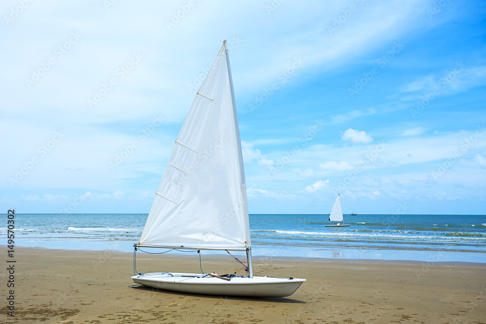 Obraz premium sailboat with tropical sand beach and cloudy blue sky on day noon light,Image for summer holiday vacation concept.