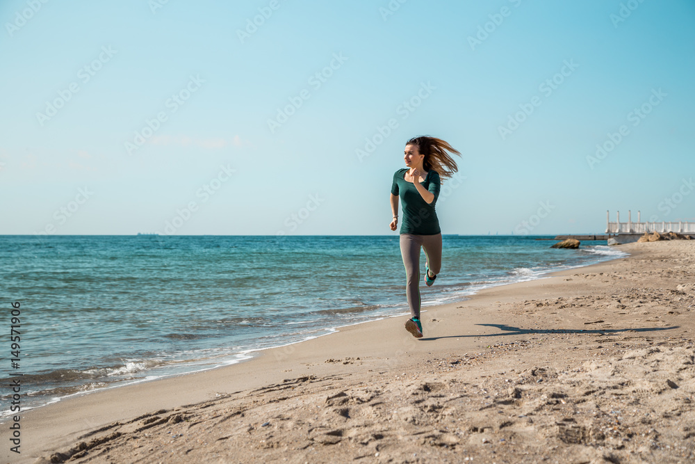 Girl in sportswear running along the sea