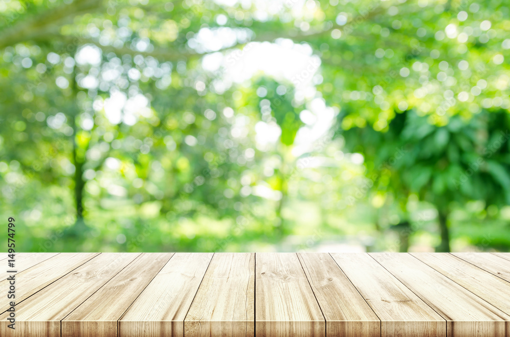 Empty wooden table top with blurred green natural background.