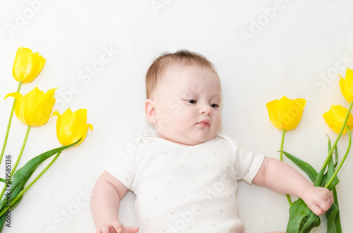 ребенок лежит возле тюльпанов