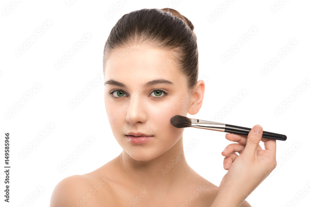 Portrait of beautiful young brunette woman with clean face. Beauty spa model girl with perfect fresh clean skin applying cosmetic brush. Youth and skin care concept. Isolated on a white background.