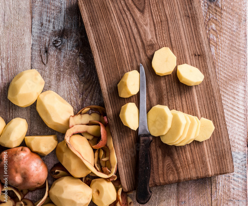 peeled and cut potato on wooden table photo