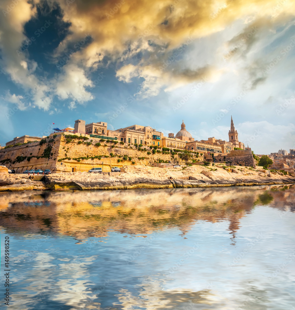 view on Valletta with its architecture from the sea at sunset with reflection