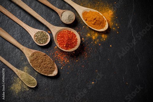 Herbs and spices and the spoon over black stone background. Top view