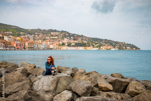 Femme sur la digue du port de Porto Santo Stefano en Toscane