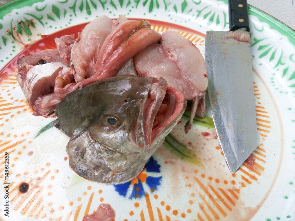 Fresh fish is cut into pieces stacked in the tray waiting for  cooking,BLACK-BANDED TREVALLY, Serolina Nigrofasciata,Knife soaked with  blood and meat of the fish Stock Photo