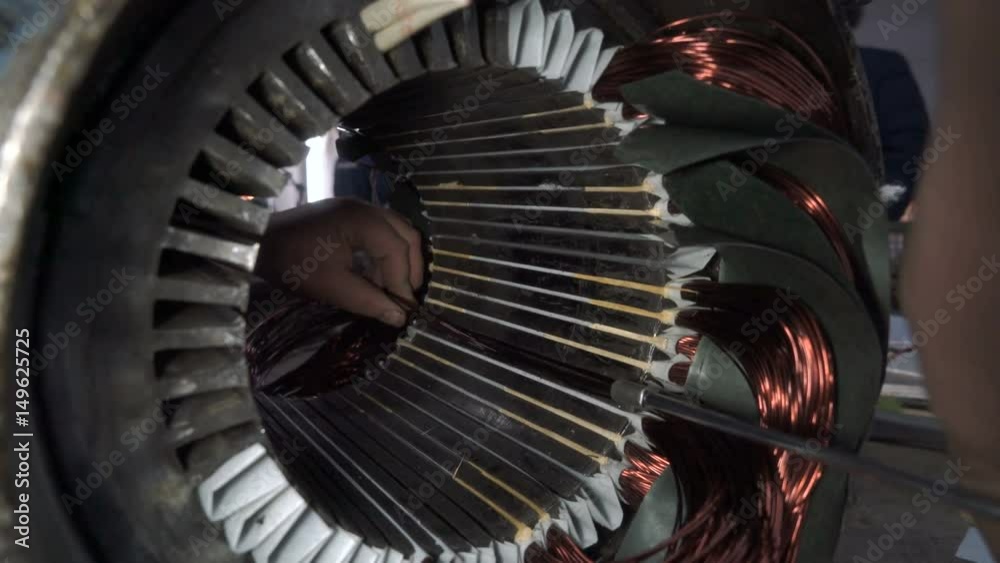 Mechanic stacks coils of the stator. Electric motor repairing.