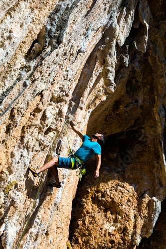 Rock Climber hanging on one hand high over the deep