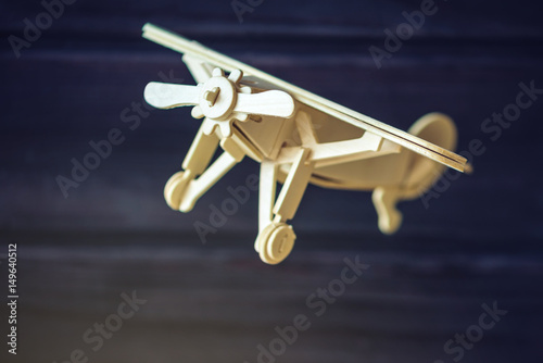 Wooden toy airplane flies on a dark background in retro style