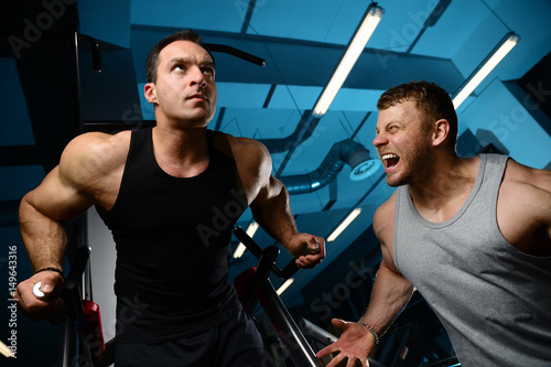 Two brutal strong athletic men pumping up muscles train gym