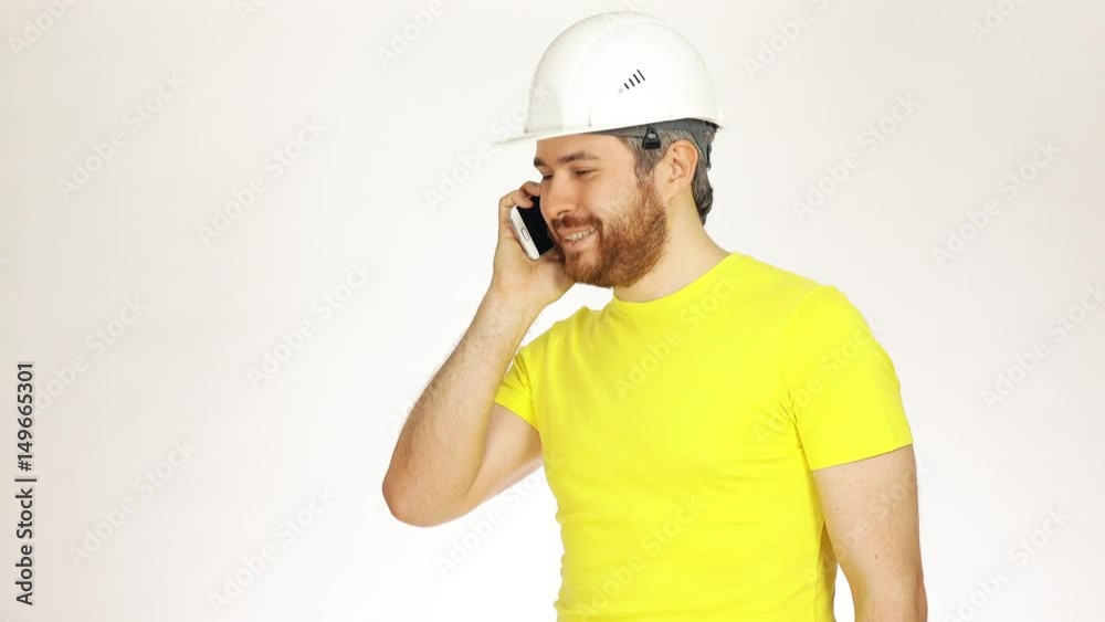 Handsome construction engineer or architect in yellow tshirt talking on his cell phone against white background. 4K video Handsome construction engineer or architect in yellow tshirt talking on his cell phone against white background. 4K video