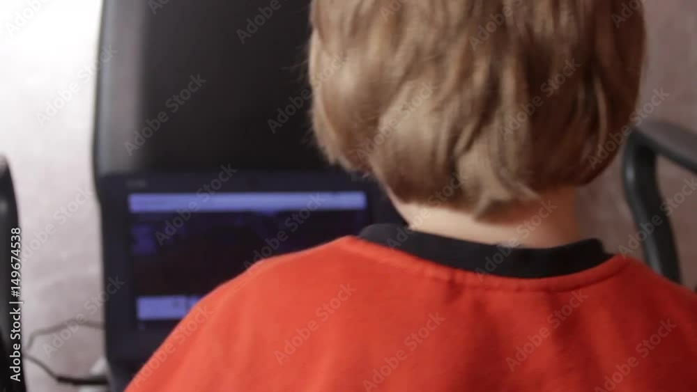 Close up of a little boy sitting on the floor and trying to learn with a computer. New generation and technology concept.