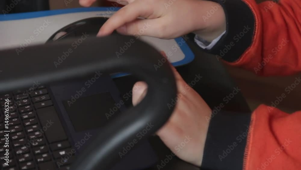 Close up of a little boy sitting on the floor and trying to learn with a computer. New generation and technology concept.