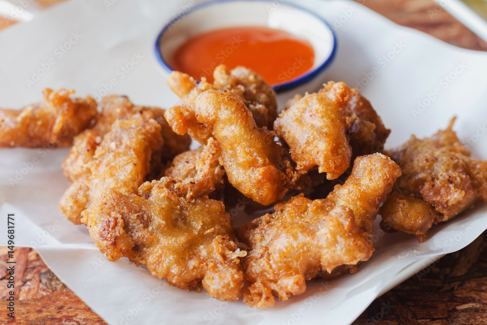 Fried chicken nuggets and chili sauce on a white plate with a wooden background. Fried chicken nuggets and chili sauce on a white plate with a wooden background.