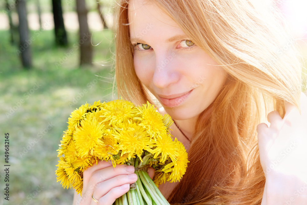Redhead woman smiling portrait with bouquet of dandelions in sunlight Redhead woman smiling portrait with bouquet of dandelions in sunlight